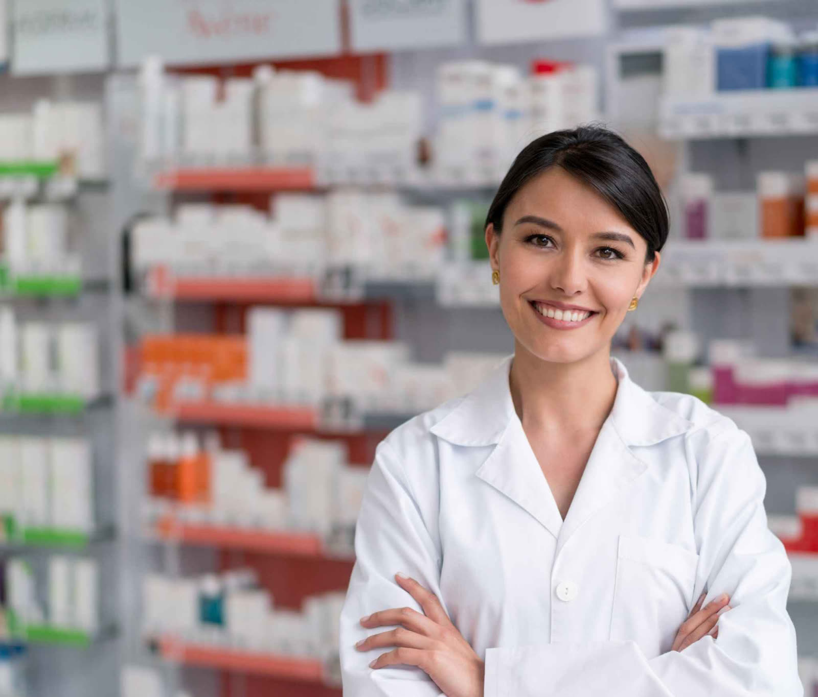 A pharmacist in front of stocked pharmacy shelves